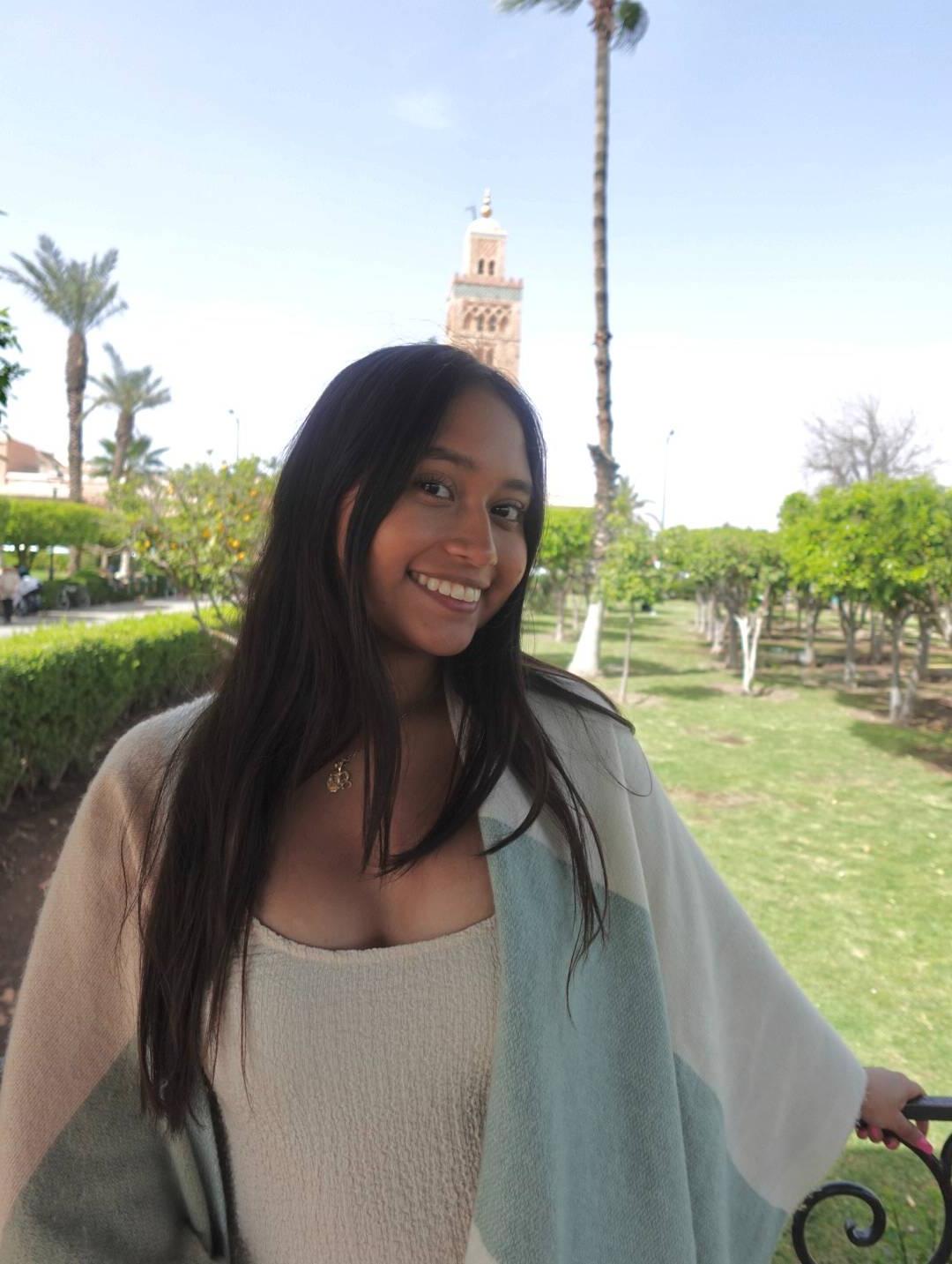 Cynthia Salas, 25岁 smiles at the camera; there are palm trees in the background.